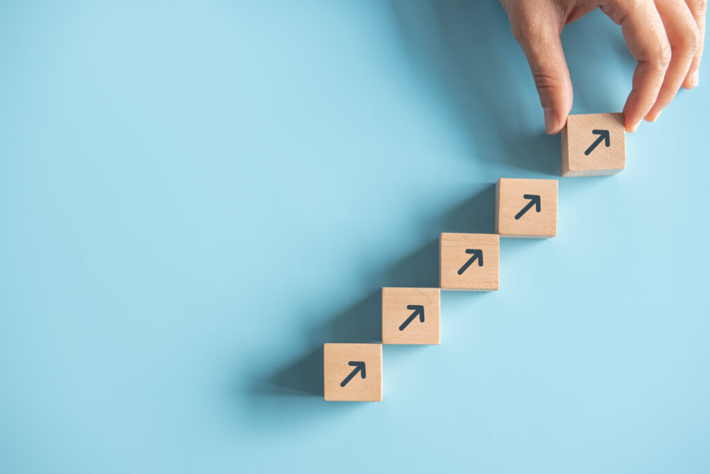 Close up man hand arranging wood block stacking as step stair on paper pink background. Business concept growth success process, copy space.